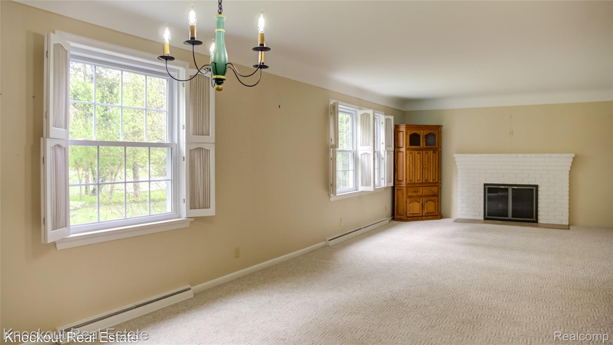 4465 Dirker Road Saginaw, MI 48638 - Photo 10 of 56 Living room with a baseboard heating unit, carpet flooring, a brick fireplace, baseboard heating, and hanging lights