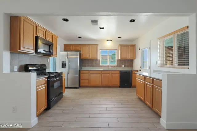 a white kitchen with stainless steel appliances granite countertop a stove top oven a sink dishwasher and a refrigerator