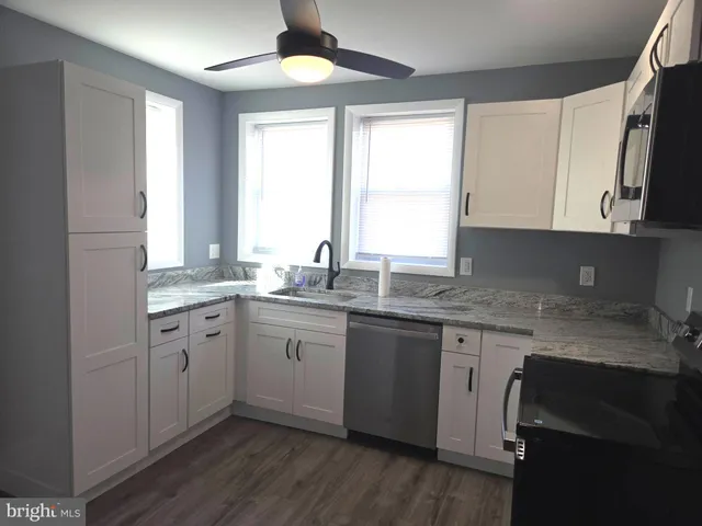 a kitchen with granite countertop cabinets stainless steel appliances a sink and a window
