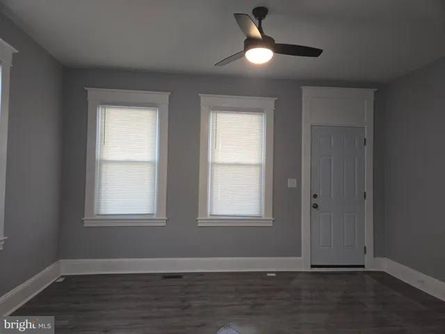 an empty room with wooden floor closet and windows