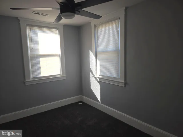 an empty room with windows and fan