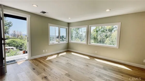 a view of an empty room with wooden floor and a window