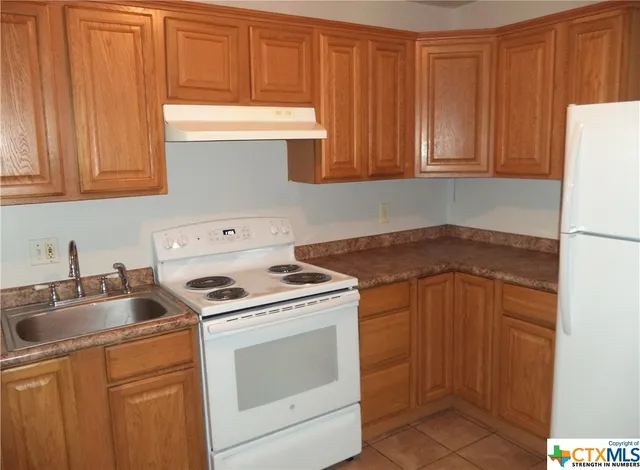 a kitchen with appliances a sink and cabinets