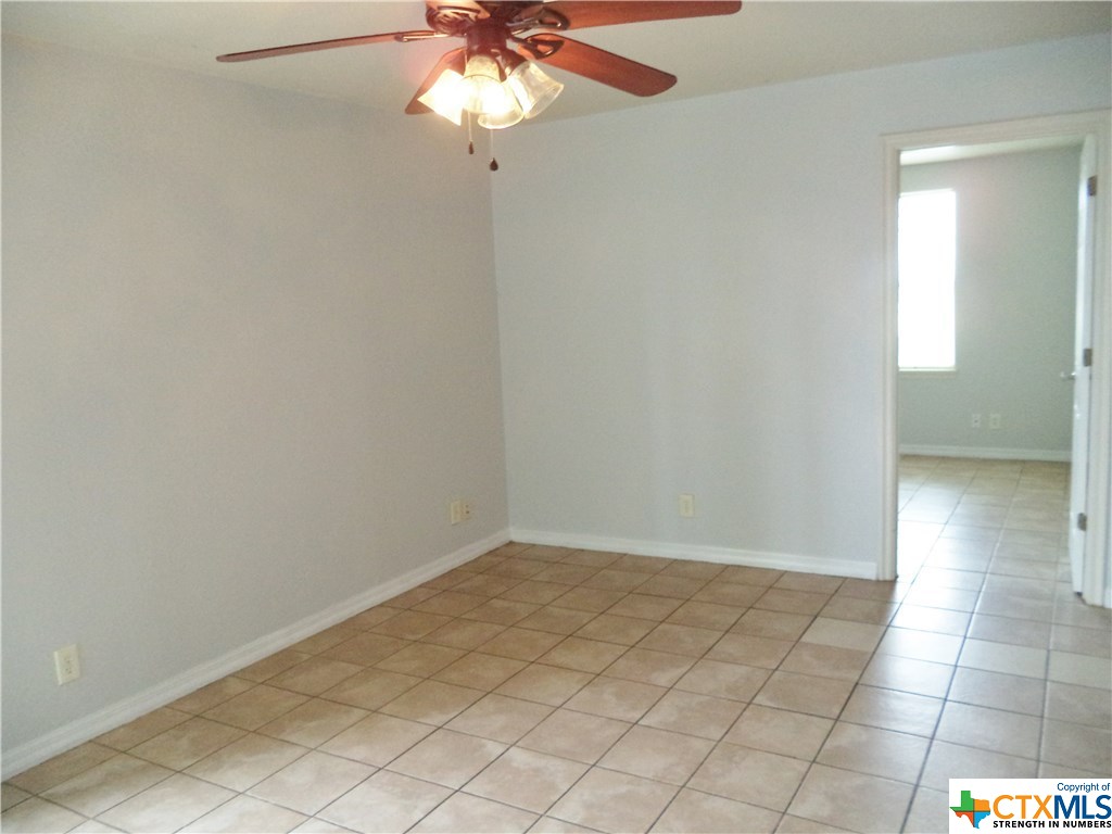 1310 West Broadway Avenue Seadrift, TX 77983 - Photo 3 of 7 an empty room with a chandelier fan and windows