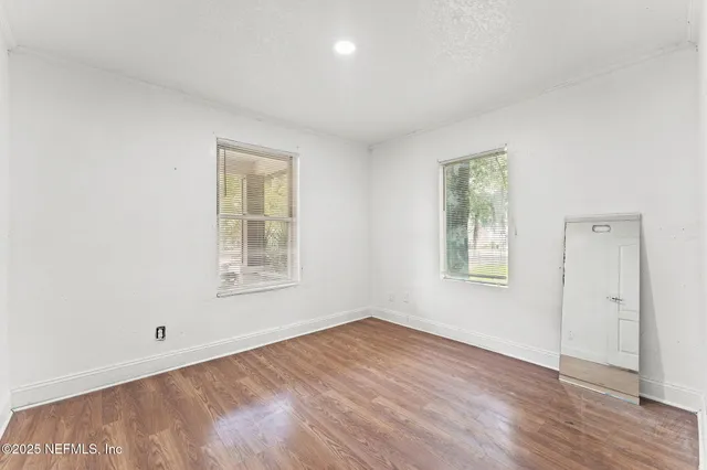 a view of an empty room with wooden floor and a window