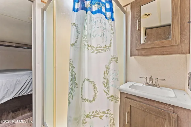 a bathroom with a granite countertop sink a mirror and shower