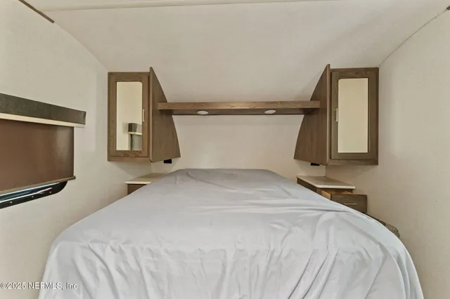 a bedroom with a bed and a flat tv screen on dresser