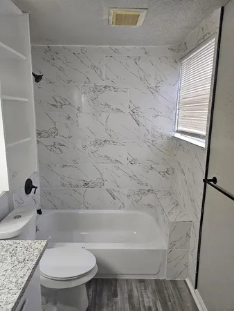 a bathroom with a granite countertop toilet a sink and a bathtub