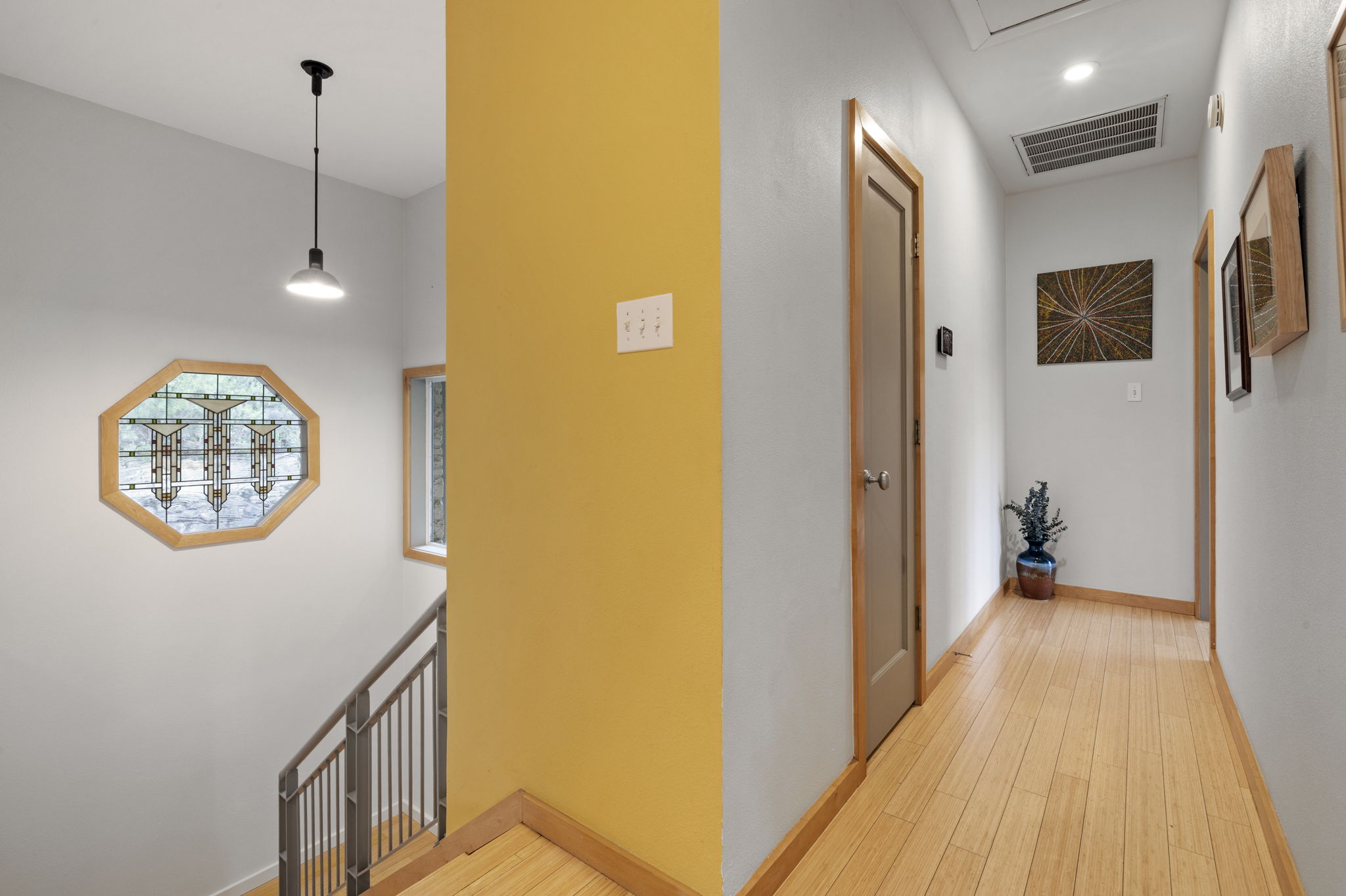 701 Yaupon Valley Road West Lake Hills, TX 78746 - Photo 23 of 40 The door on the left is for the half bathroom. The door on the right at the end of the hallway is for the primary suite. Go downstairs for the secondary bedrooms. Note the interesting glass window in the stairwell.