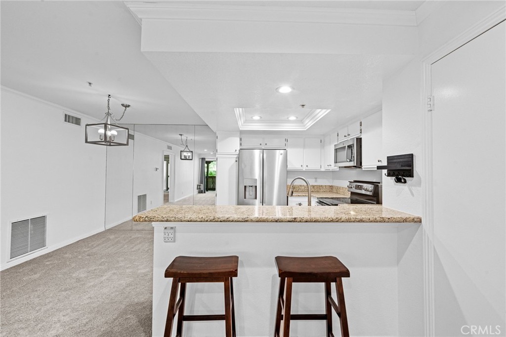 215 South Cross Creek Road, Unit L Orange, CA 92869 - Photo 35 of 50 a large white kitchen with granite countertop lots of counter top space and chandelier