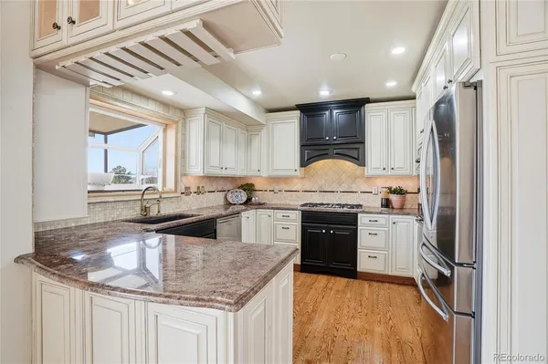 a kitchen with stainless steel appliances granite countertop a sink a stove and a refrigerator