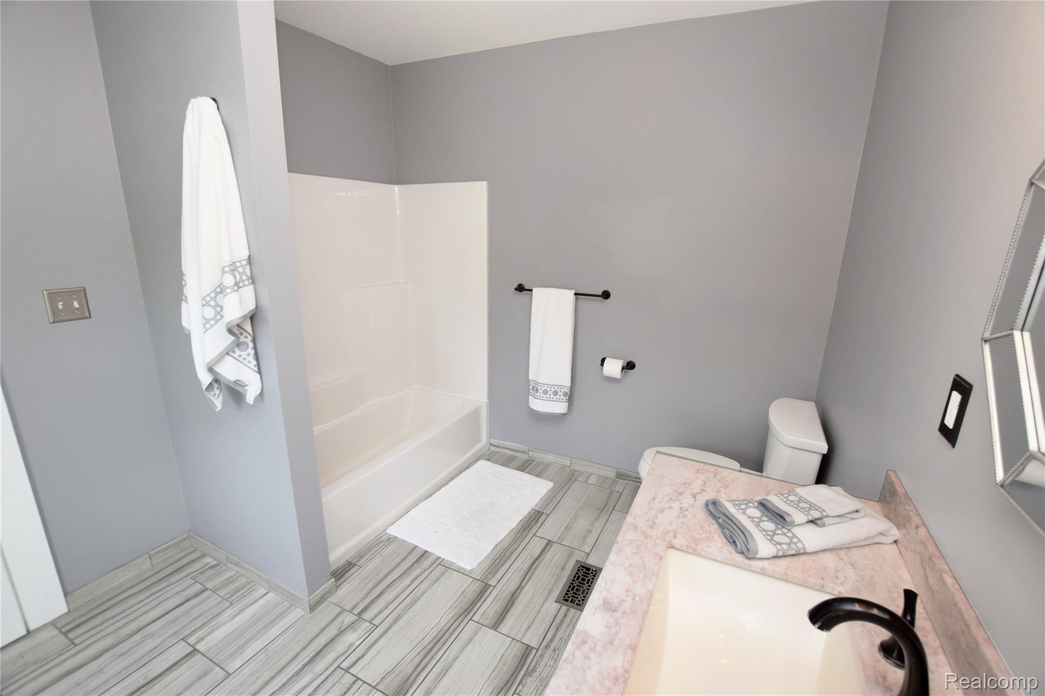404 North Adelaide Street Fenton, MI 48430 - Photo 18 of 23 Bathroom featuring a white tub/shower combination, light gray wall paint, and wood-finish flooring