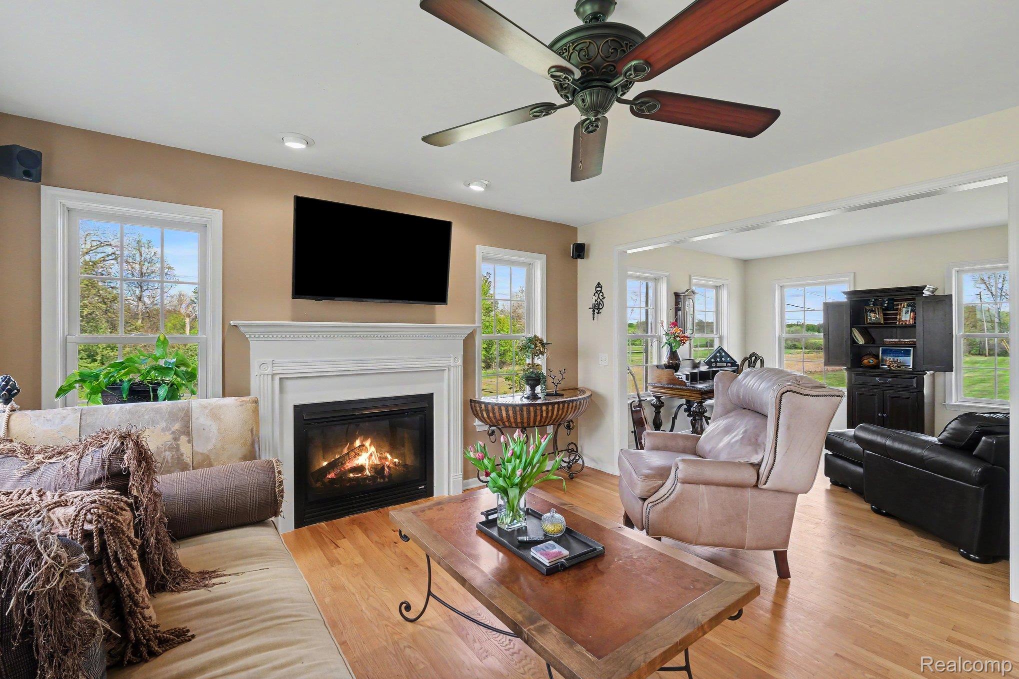 6520 Cook Road Swartz Creek, MI 48473 - Photo 12 of 43 Living area featuring healthy amount of natural light, light wood finished floors, a glass covered fireplace, and a ceiling fan
