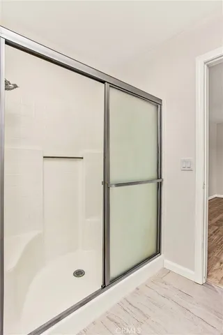 a view of an empty room with wooden floor and a bathroom
