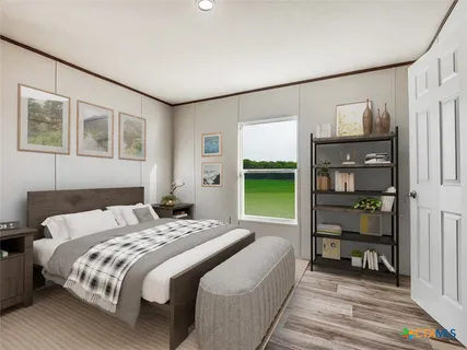 a bedroom with a bed a table and potted plant with the wooden floor
