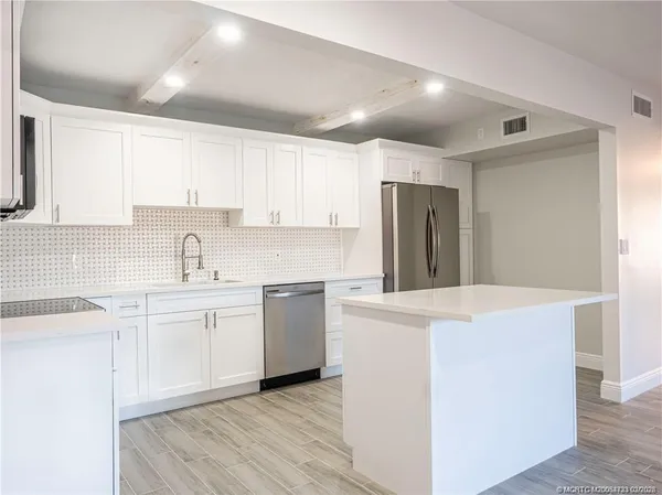 a kitchen with a sink a stove a refrigerator and white cabinets