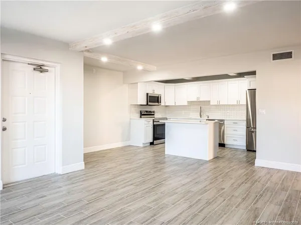 a view of kitchen view wooden floor and stainless steel appliances