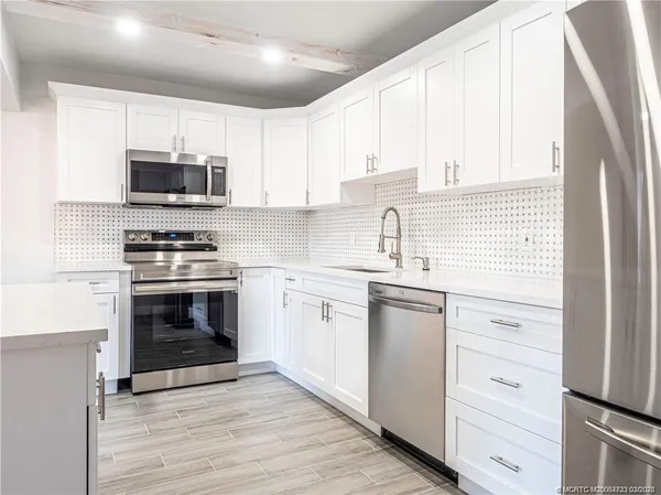 a kitchen with white cabinets and stainless steel appliances