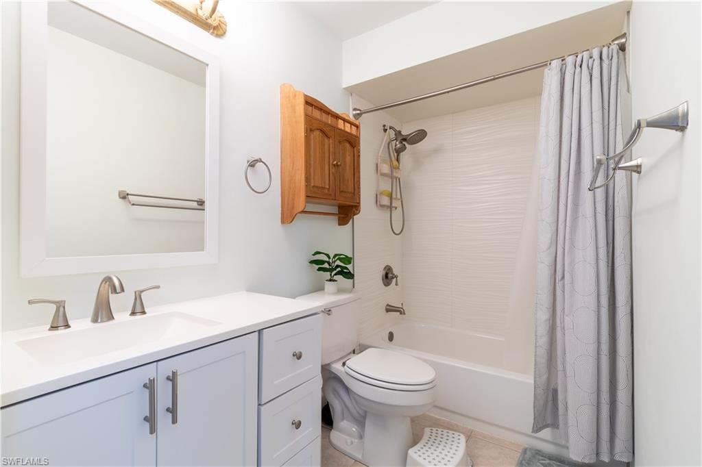 1014 Pine Isle Lane, Unit 1014 Naples, FL 34112 - Photo 15 of 20 a bathroom with a sink a toilet a mirror a vanity and shower