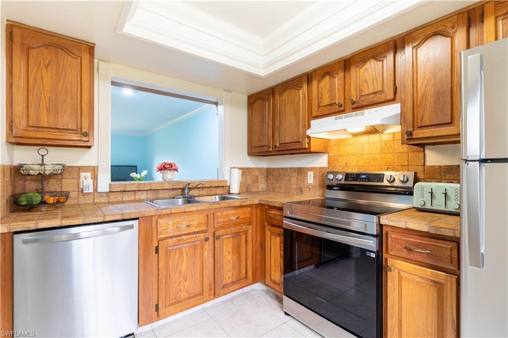 1014 Pine Isle Lane, Unit 1014 Naples, FL 34112 - Photo 4 of 20 a kitchen with stainless steel appliances granite countertop a sink stove and cabinets
