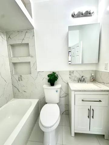 a bathroom with a granite countertop sink a toilet and bathtub