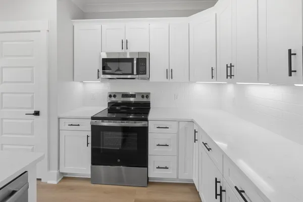 a kitchen with stainless steel appliances granite countertop white cabinets and a stove
