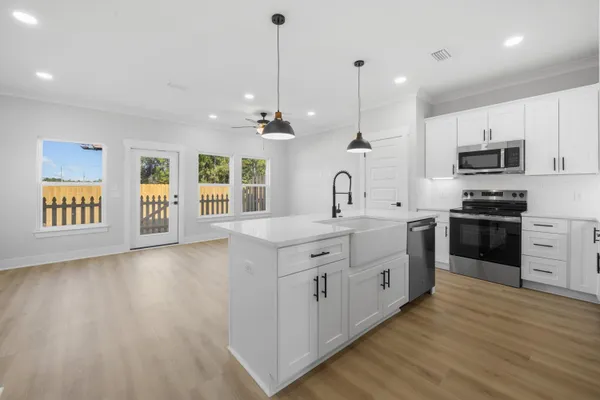 a large kitchen with stainless steel appliances granite countertop a stove a sink a refrigerator and a wooden floors