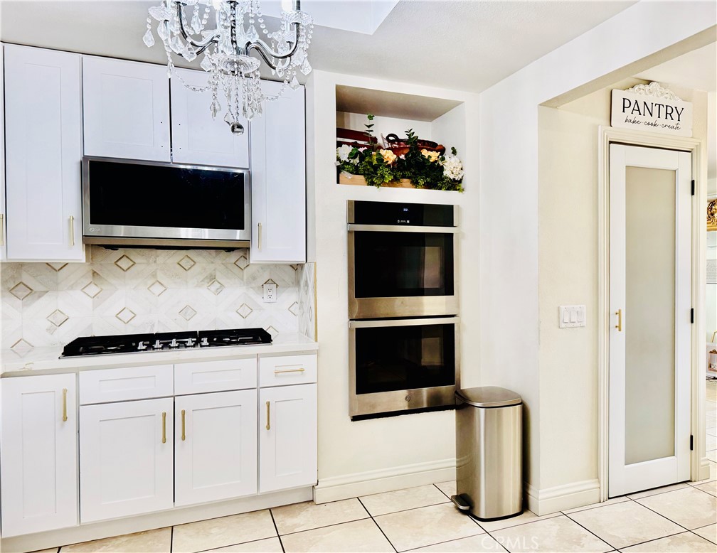 8735 Calaveras Avenue Rancho Cucamonga, CA 91730 - Photo 14 of 52 a kitchen with white cabinets and stainless steel appliances