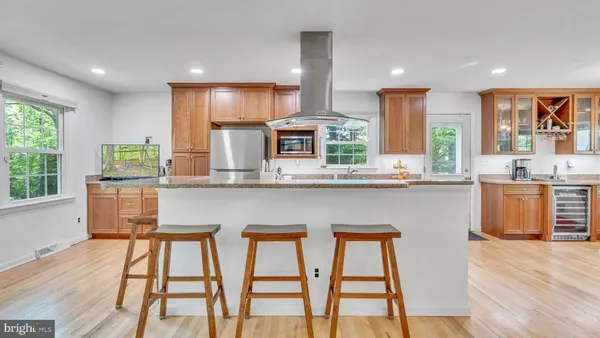 a kitchen with stainless steel appliances granite countertop wooden floor a window cabinets and a kitchen island