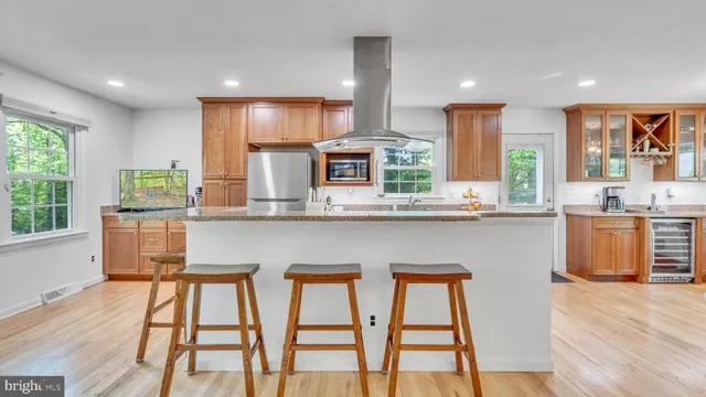 a kitchen with stainless steel appliances granite countertop wooden floor a window cabinets and a kitchen island