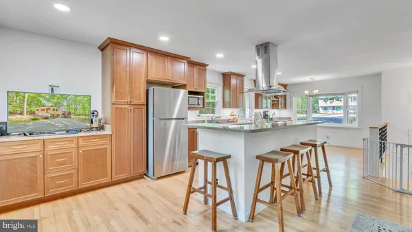 a kitchen with stainless steel appliances granite countertop a refrigerator a sink dishwasher a dining table and chairs with wooden floor