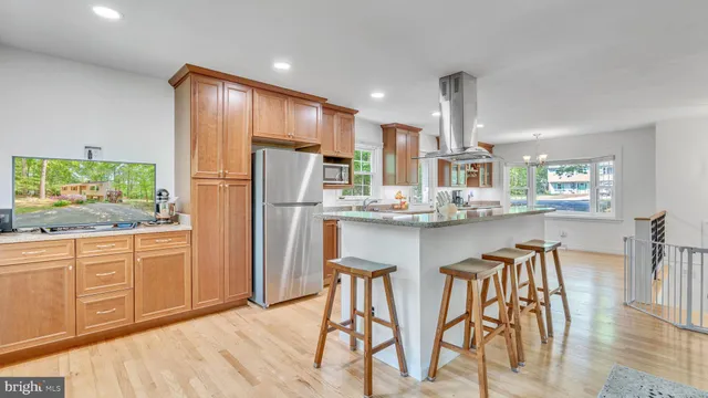 a kitchen with stainless steel appliances granite countertop a refrigerator a sink dishwasher a dining table and chairs with wooden floor