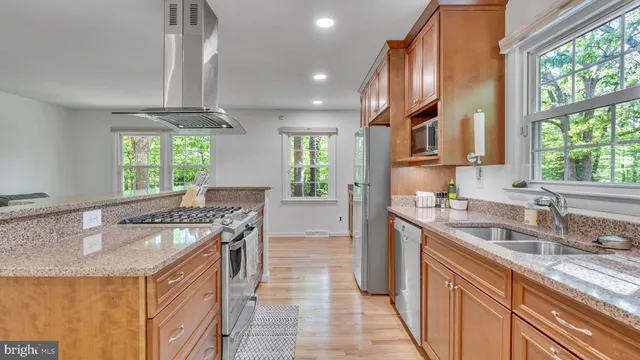 a kitchen with stainless steel appliances granite countertop a sink a stove and a refrigerator