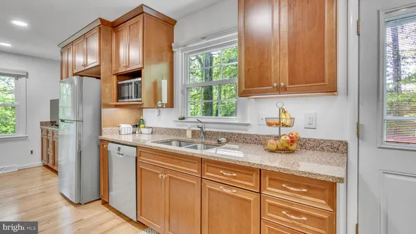 a kitchen with stainless steel appliances granite countertop a sink a refrigerator and cabinets