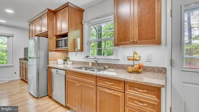 a kitchen with stainless steel appliances granite countertop a sink a refrigerator and cabinets