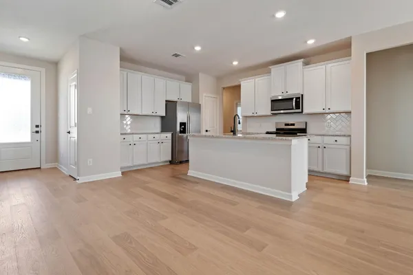 a kitchen with cabinets and wooden floor
