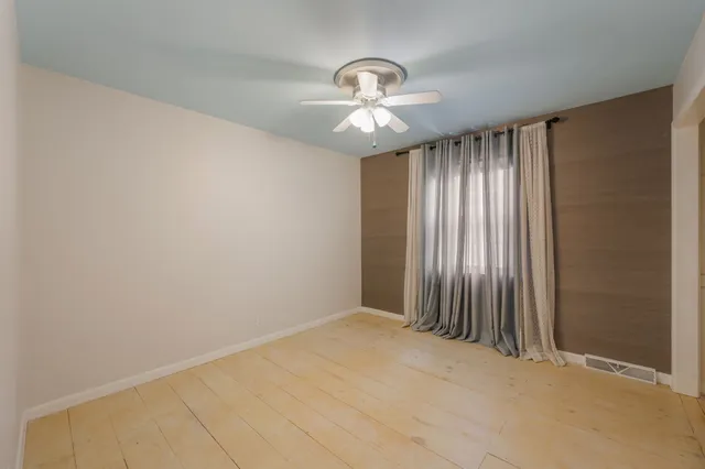 an empty room with chandelier fan and windows