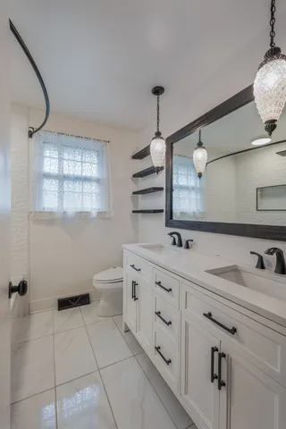 a bathroom with a double vanity sink mirror and toilet