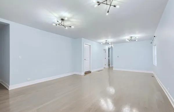 wooden floor in an empty room with a chandelier fan