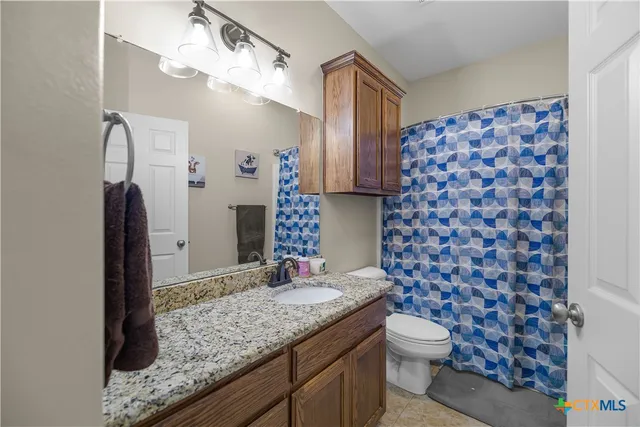 a bathroom with a granite countertop toilet a sink and a mirror