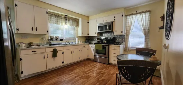 a dining room with wooden floor a chandelier a wooden table and chairs