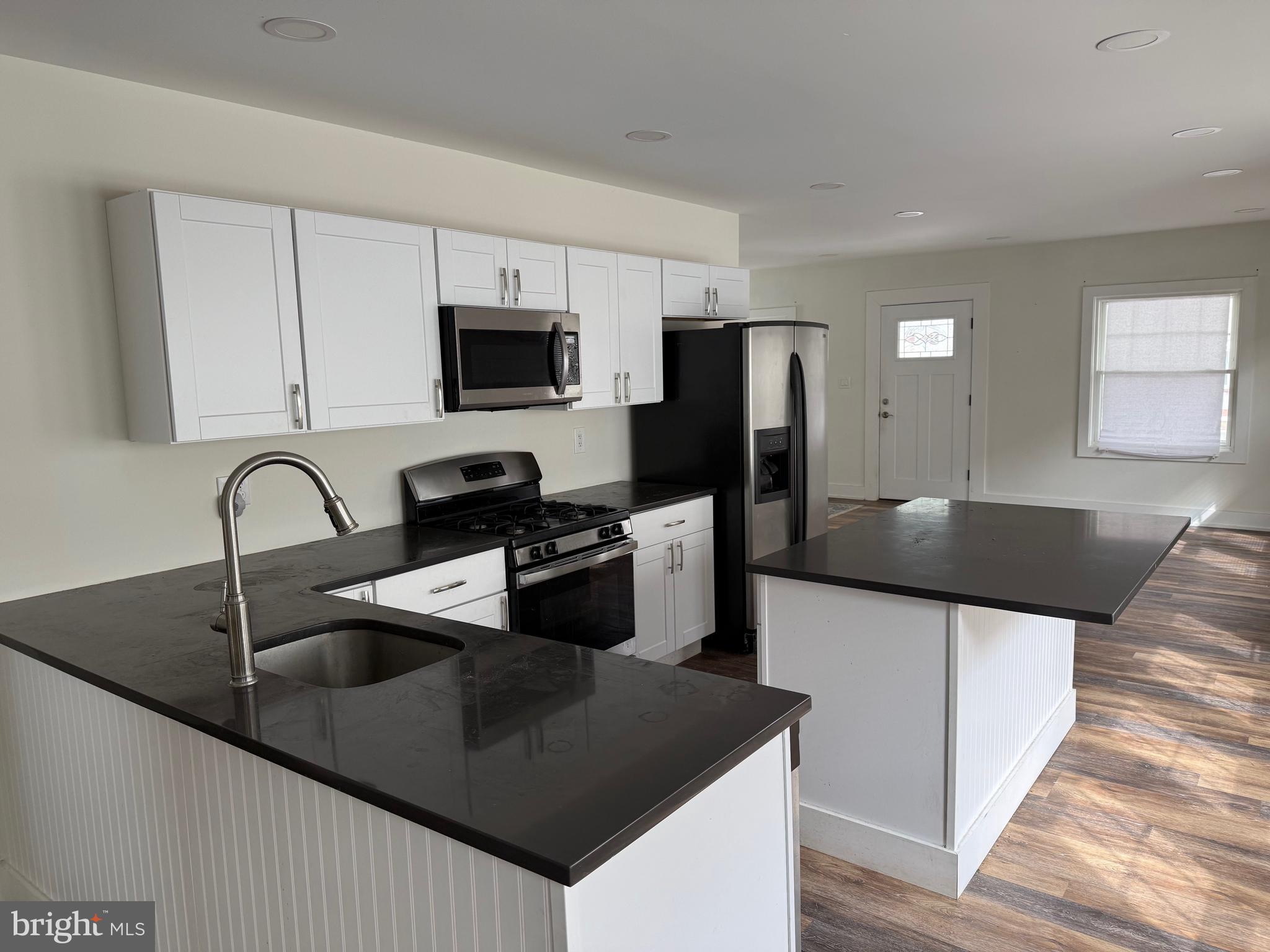 132 Walnut Street Westville, NJ 08093 - Photo 9 of 23 a kitchen with stainless steel appliances granite countertop a sink a microwave a refrigerator and white cabinets