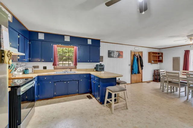 a kitchen with stainless steel appliances granite countertop a table chairs sink and cabinets