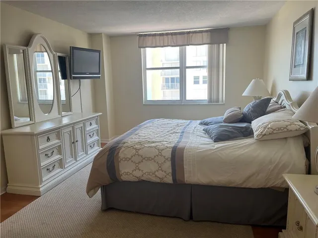 a bedroom with a bed window and mirror
