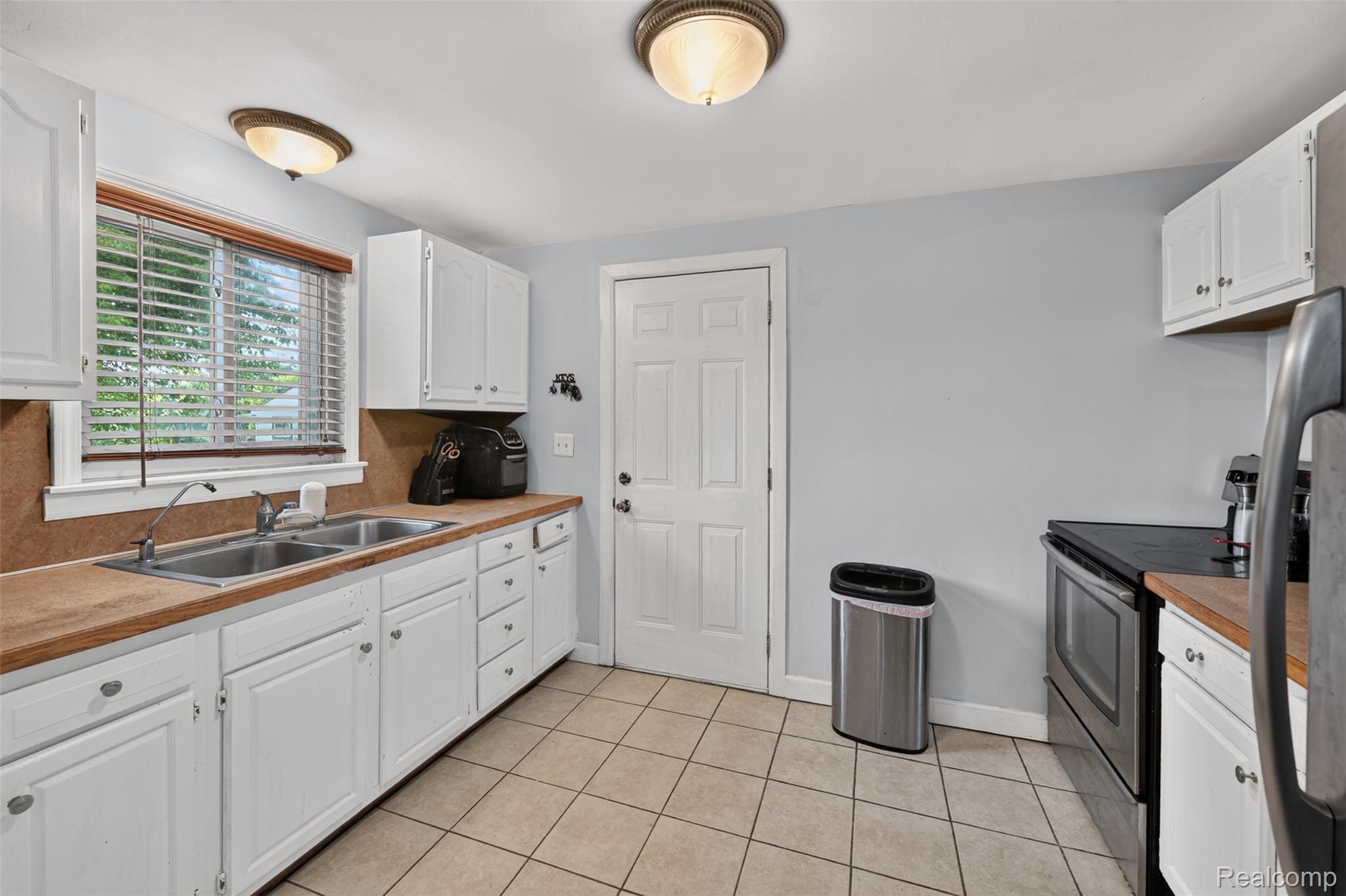7369 North Webster Road Mount Morris, MI 48458 - Photo 27 of 56 Kitchen featuring white cabinetry, wood-finish countertops, stainless steel appliances, and tile flooring