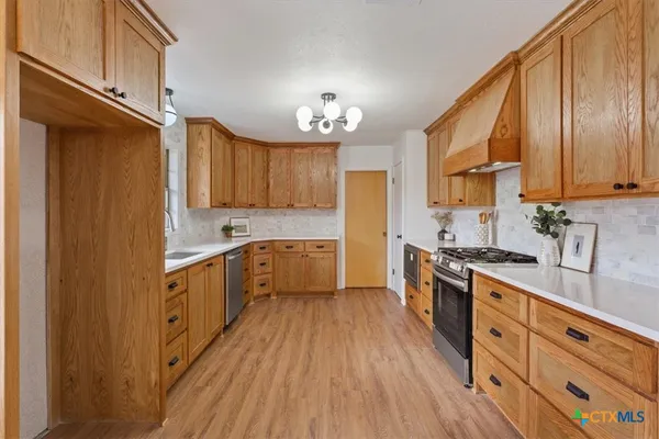 a kitchen with stainless steel appliances granite countertop a stove a sink dishwasher and a refrigerator with wooden floor