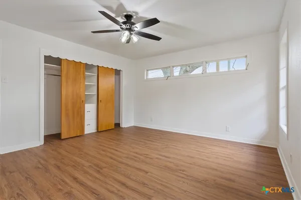 an empty room with wooden floor and windows