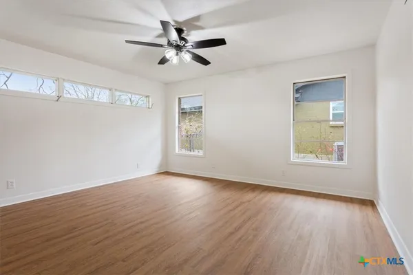 a view of an empty room with wooden floor and a window