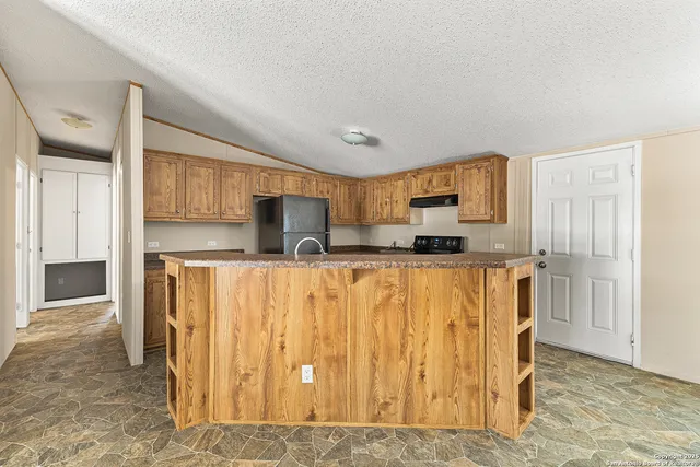 a view of kitchen with stainless steel appliances granite countertop a refrigerator and a stove top oven
