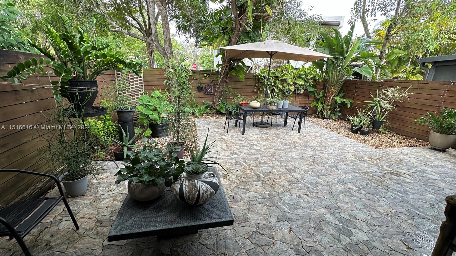 a view of a patio with table and chairs potted plants and large tree